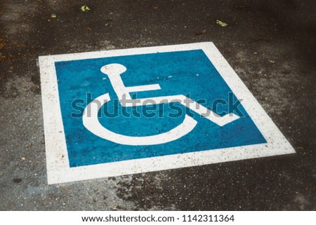 Blue and white disabled design painted on the ground, public parking lot, vintage look, usa.