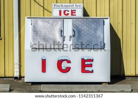 Packaged Ice freezer machine against a yellow wall during a hot and sunny day of summer outside a grocery store, Oregon, USA. Royalty-Free Stock Photo #1142311367