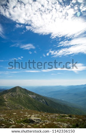 Striking landscape photography of stunning mountain ranges along the Appalachian trail on a beautiful blue sky and sunny day. Views from Franconia Ridge Loop, Mount Lafayette traverse nature trail