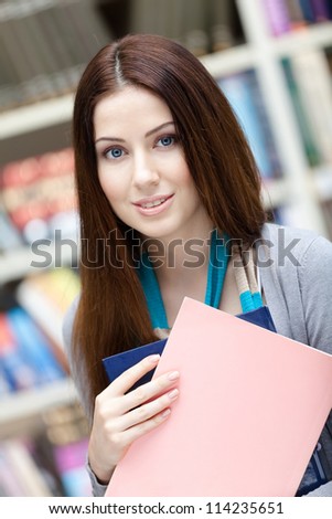Young female student with books at the library. Research. Learning