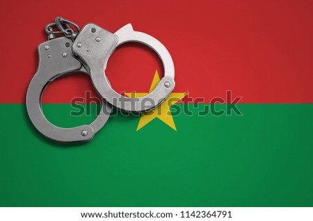 Burkina Faso flag  and police handcuffs. The concept of crime and offenses in the country