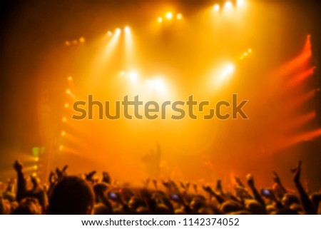 Musical concert. People in the concert hall at the disco . Singer in front of the audience. Fans at the concert. Blurred image / blurred photo.  Royalty-Free Stock Photo #1142374052