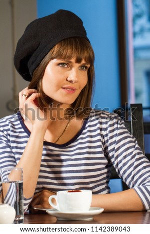 young girl is sitting at a table in a cafe