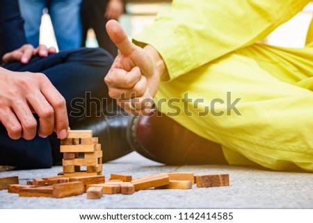 The business team and engineers plays Jenga game that compares how to co-operation between business team and engineers build the building together.He show hand good.Photo concept team and engineers.