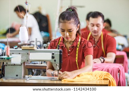 portrait of professional Seamstress in textile factory sewing with industrial sewing machine at garment Royalty-Free Stock Photo #1142434100