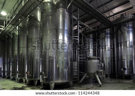Stainless steel wine vats in a row inside the winery.