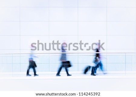 Many unrecognizable business people in front of modern architecture, intentional motion blur, blue tinted high resolution stock photo