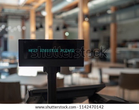 A cash register in airy eatery displaying next register please sign