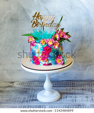 Tropical birthday cake on a cakestand with a topper