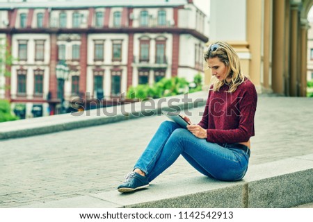 A woman in the city with a tablet .The girl uses new technologies for work and rest