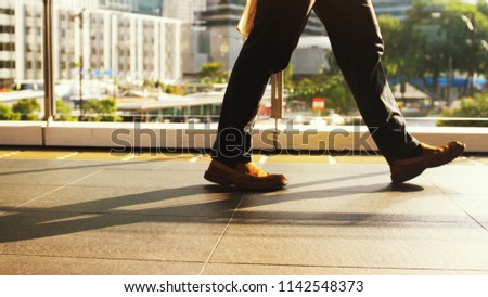 Man's feet walk on pedestrian crossing on a busy day in the center of the city on a sunny day on the road on the background