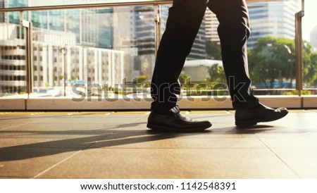 Businessman's feet walk on pedestrian crossing on a busy day in the center of the city on a sunny day on the road on the background
