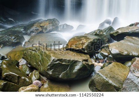 cold river waterfall cascade falling down on stones in national reserve park Thailand
