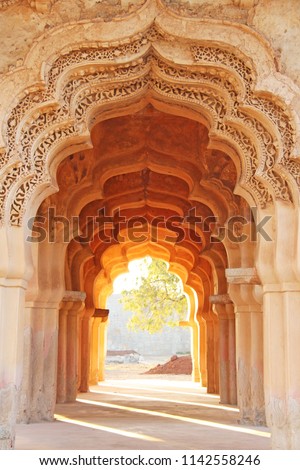 Lotus Mahal Temple in Hampi, Karnataka, India. Beautiful carved stone arch and sunset. A popular tourist route from the GOA state. Beautiful hindu temple. Royalty-Free Stock Photo #1142558246
