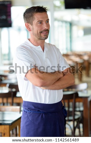 barista smiling at camera with arms crossed in the bakery