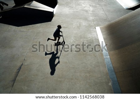 silhouette of Jumping on a kick scooter silhouette teen on gray concrete extreme area background.