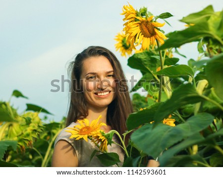 Beautiful smiling woman in yellow sunflowers