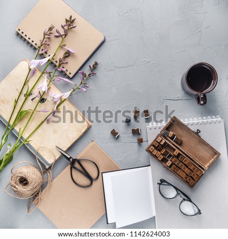 Hipster student objects flatlay with book, plants, leaves, glasses, cards, coffee cup, frame, flower, notebook. Creative work table for photographer, traveller, blogger. Working space surface top view