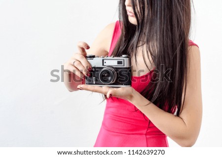 Portrait of a beautiful girl, black hair, red dress, holding in her hands an old vintage photo camera