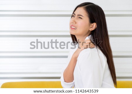 Asian girls gesture to touching demonstrating suffering from ache neck and shoulder pain and injury. female neck pain and feeling her back tired working. office syndrome and health care concept.