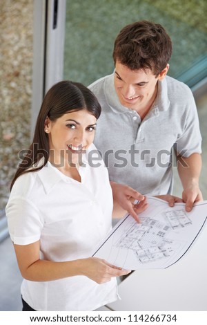 Happy attractive couple holding architectural drawing in their hands