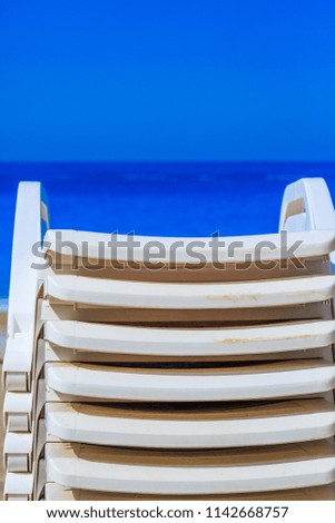 Sea view. A stack of sun loungers on the beach. Minimalism. 