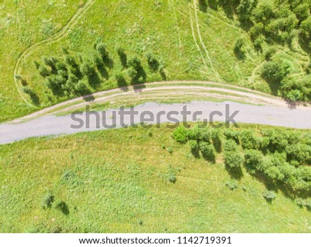 Aerial photo of the dirt road in a partially wooded countryside field