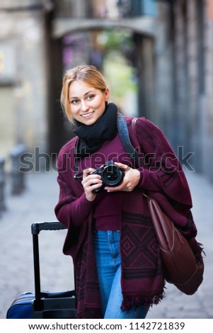 Young positive cheerful woman looking curious and taking pictures outdoors