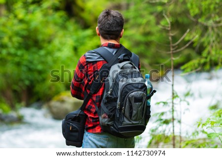 Young man looks at a stream of a mountain river.