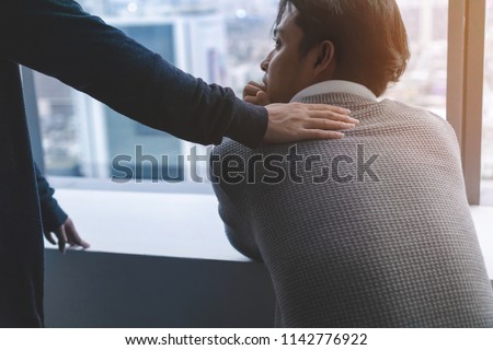 PTSD Mental health concept, Psychologist sitting and touch young depressed asian man for encouragement near window with low light environment.Selective focus. Royalty-Free Stock Photo #1142776922