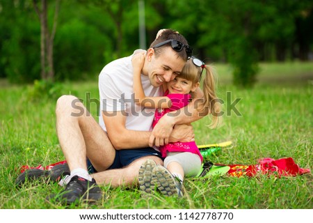 Little girl embracing her father during walk in park on summer day. Happy childhood with father