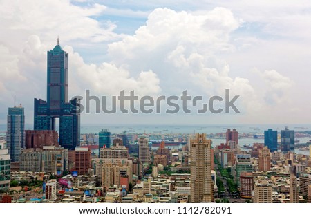 Cityscape of Kaohsiung Downtown, a vibrant seaport city in Southern Taiwan, with the landmark 85 Sky Tower standing out among modern buildings and ships parking in the harbor under cloudy sunny sky