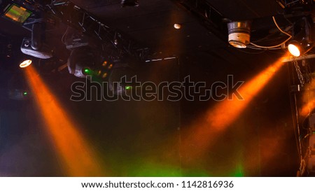 Scenic lights with strong beams in smoke over dark background, modern stage illumination equipment
