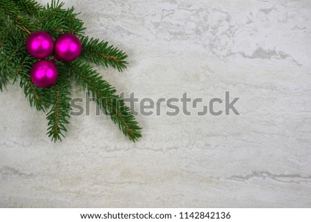 Three fuscia Christmas ornaments on a spruce bough in the upper left corner  with copy space