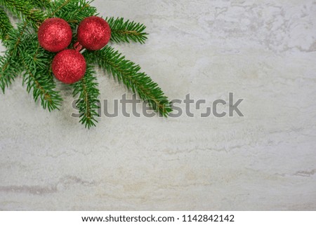 Three red glittery Christmas ornaments on a spruce bough in the upper left corner  with copy space