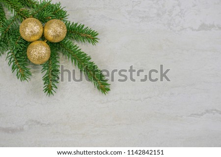 Three gold glittery Christmas ornaments on a spruce bough in the upper left corner  with copy space