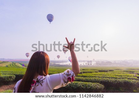 Shadow image,The girl holds her hands up over the sky to show the symbol of Love Love on the background of the tea plantations and hot air balloons floating above the sky on Valentine's Day.