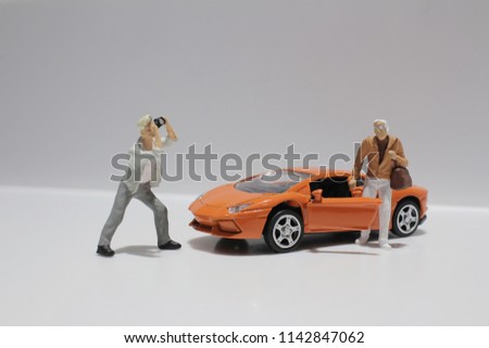  the small figure with the toy sport car