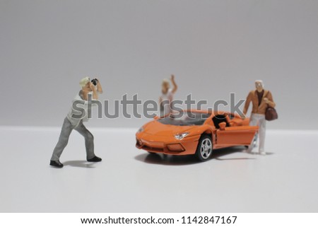  the small figure with the toy sport car