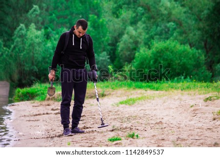 Man looking for precious metals with metal detector  Royalty-Free Stock Photo #1142849537