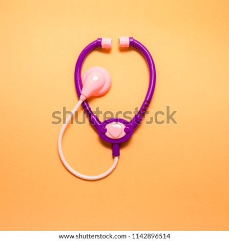 Medical phonendoscope (stethoscope) on orange background.