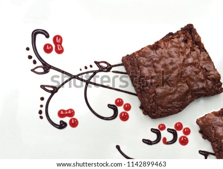 Chocolate brownie Chocolate sauce, strawberry sauce White plate