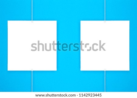 Paper cards (photo frame) hanging on metal rope with magnets on blue background