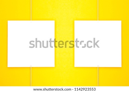Paper cards (photo frame) hanging on metal rope with magnets on yellow background