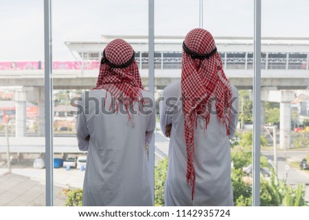 Two Arabian businessman standing back looking to big project building