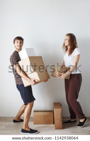 Young cute couple just married in a new apartment after repair among the cardboard boxes are happy and smiling.