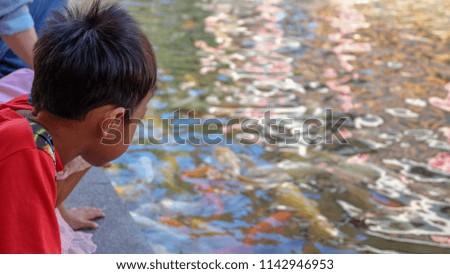 The boy is watching the fish closely.