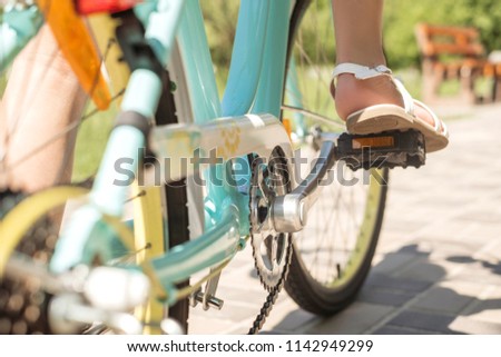 Cute little 10 years old girl in casual outfit playing at park in warm summer day. She having fun riding a bicycle