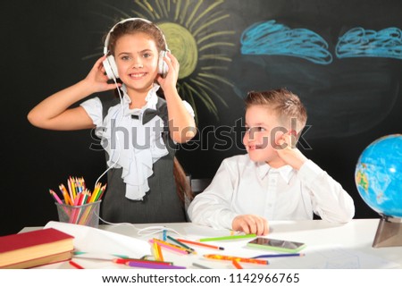 Boy and girl at school,students with books at the Desk. New academic year. Primary education. Photos in the room. School style. Children. Disciples.A boy and a girl listen to music on headphones.