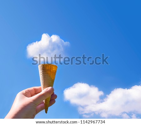 Picture of woman holding ice cream cone in the sky with fluffy cloud on the top of cone